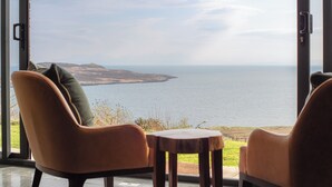 A room with two chairs and a small table, overlooking a body of water and distant land. - The Flodigarry Hotel in the Skye  (Staffin)