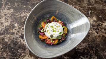 A dish with a white sauce and vegetables on a textured surface.