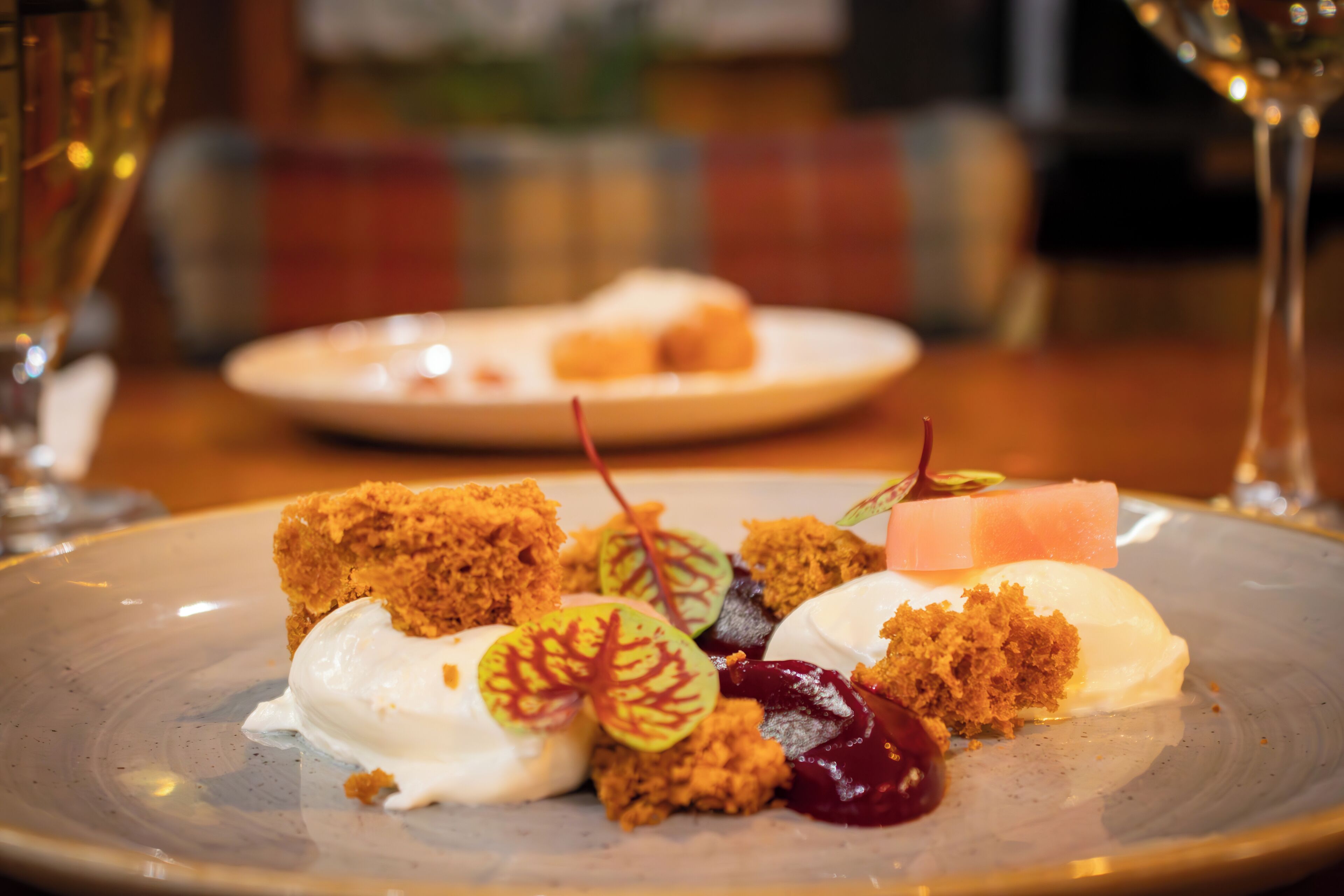 Un plato de postres con varios dulces y una copa de vino.