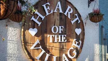 A wooden sign with the text "Heart of the Village" surrounded by heart shapes.