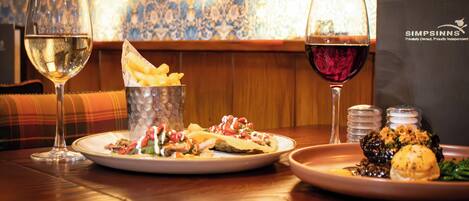 Une table à manger avec deux assiettes de nourriture, deux verres de vin et un présentoir à menus.