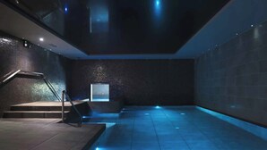 A modern indoor pool area with a staircase, tiled walls, and recessed lighting. - The Kinmel & Kinspa (Abergele)
