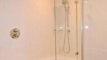 A modern bathroom with a glass-enclosed shower, a white bathtub, and a toilet.