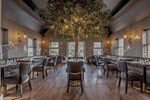 A restaurant with a central tree, booths, and tables. - The Kinmel & Kinspa (Abergele)