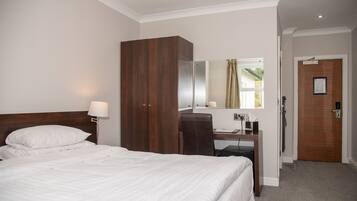 Ein Hotelzimmer mit Bett, Schreibtisch, Stuhl, Kleiderschrank, Spiegel und Tür.