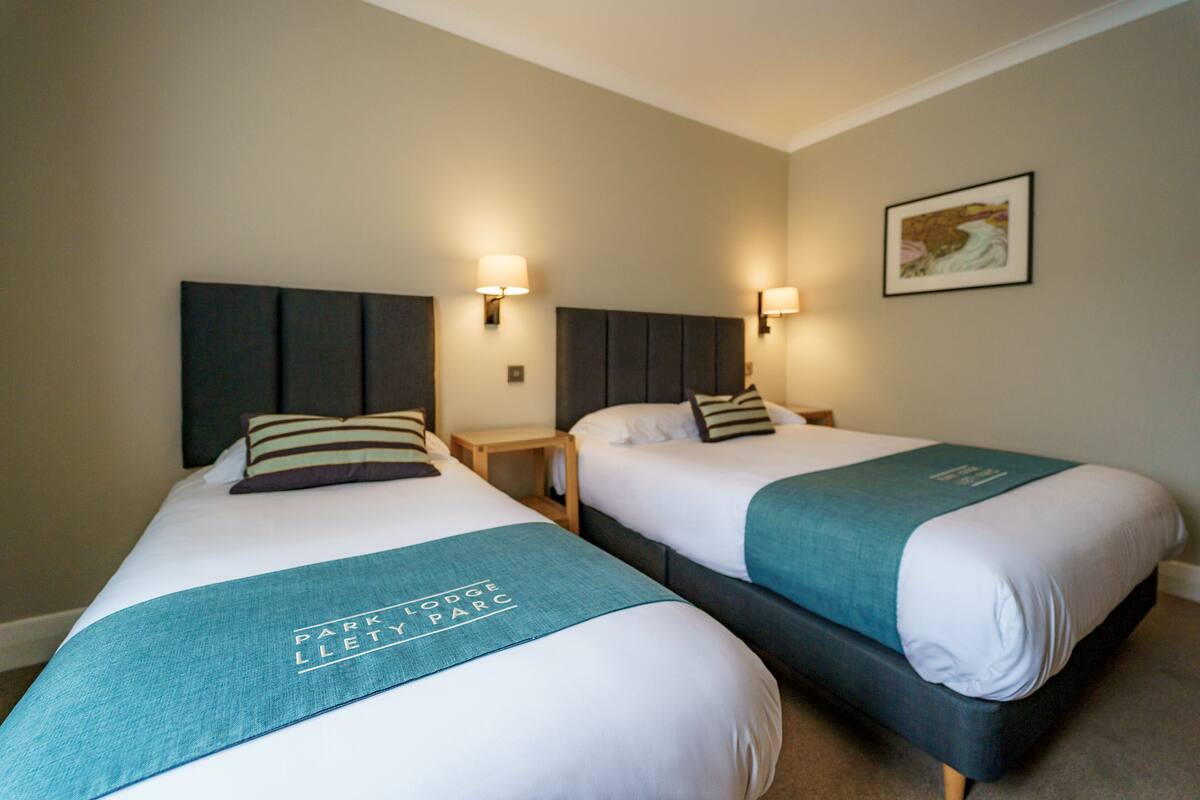 Two twin beds with headboards, bedside tables, and wall-mounted lamps.