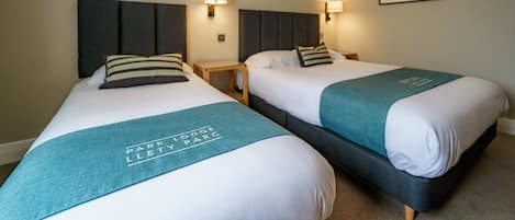 Two twin beds with headboards, bedside tables, and wall-mounted lamps.