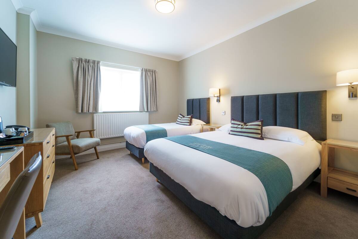 A hotel room with two beds, a desk, and a chair.