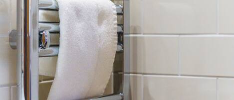 A towel rack with a white towel hanging on it, a metallic handle, and a tiled wall in the background.