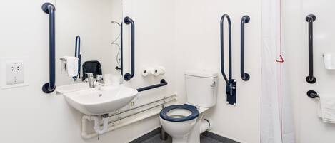 A modern bathroom with a white sink, toilet, and shower. It includes grab bars and a mirror.