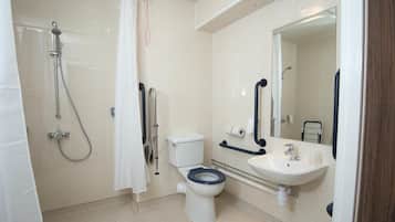 A bathroom with a shower, toilet, sink, and mirror.