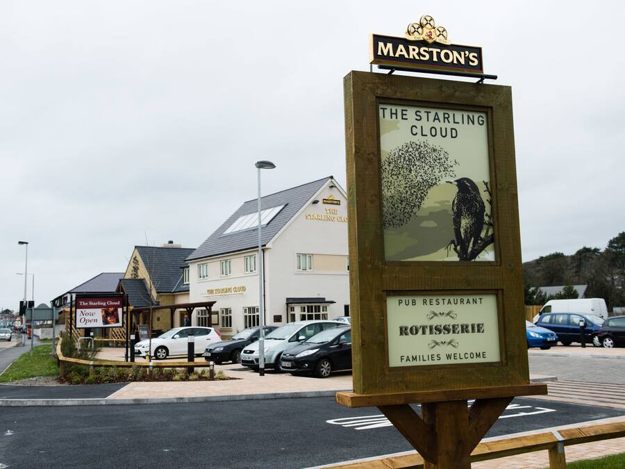 A signboard for 'The Starling Cloud' pub and restaurant with a logo, welcoming families.