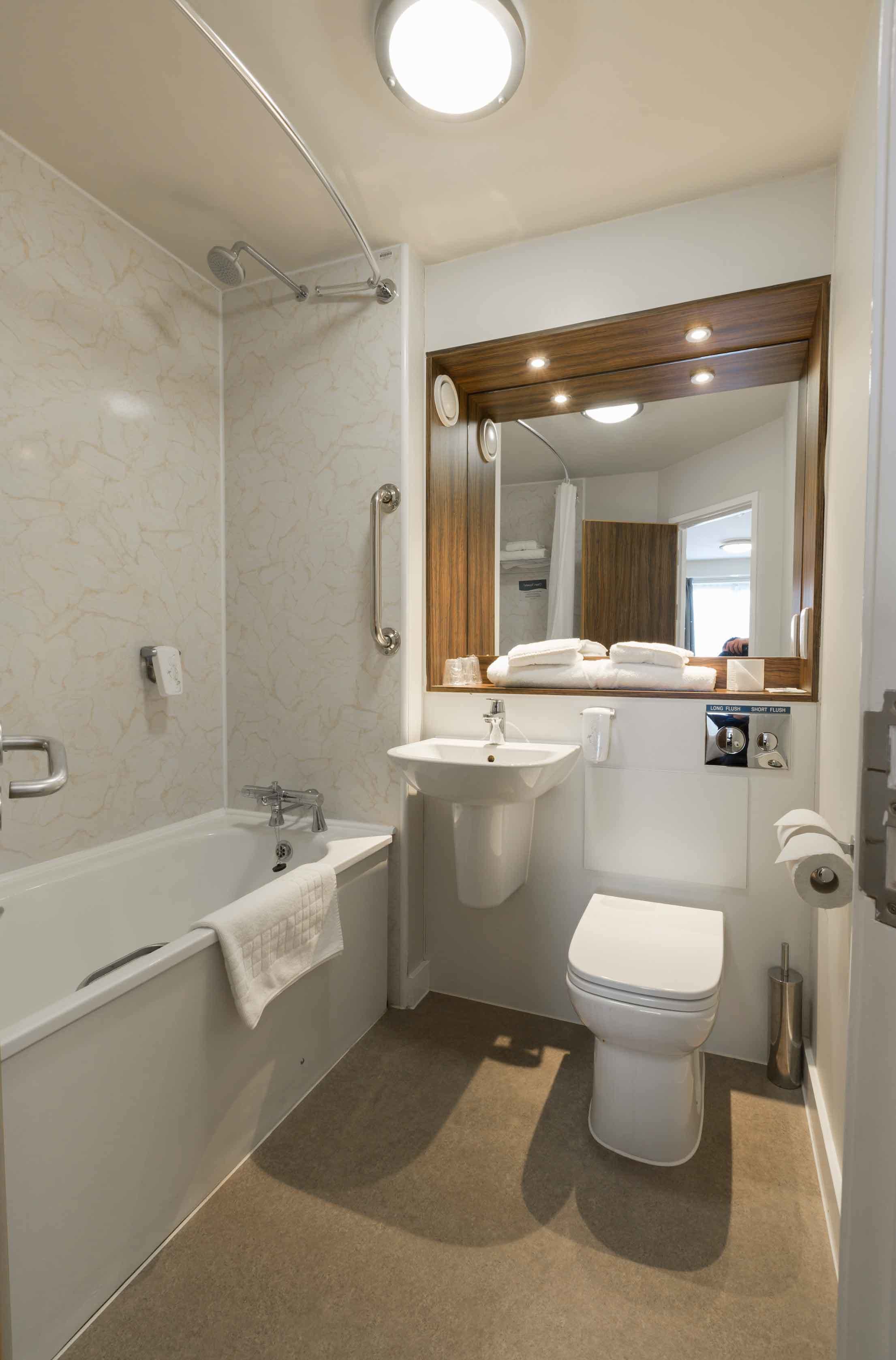 A compact bathroom with a bathtub, sink, and toilet.