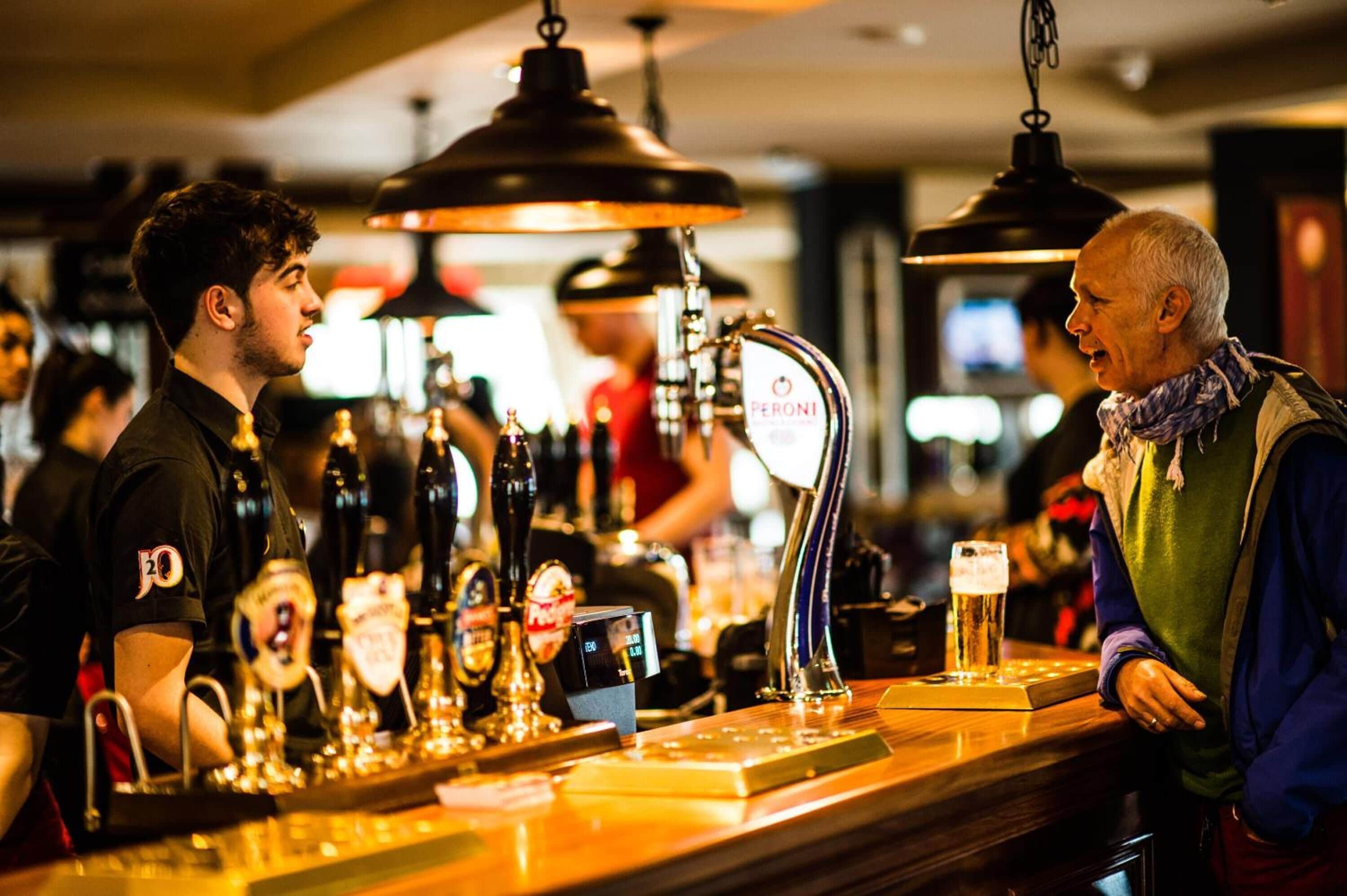 A bar with multiple beer taps and a glass of beer on the counter.