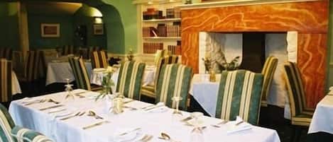A restaurant with striped chairs, white tablecloths, and a chandelier.