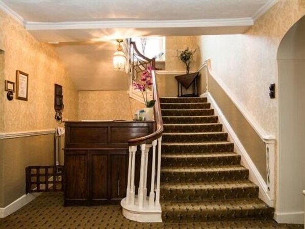 A staircase with a wooden handrail and carpeted steps leading to an upper floor. - Bishopsgate House Hotel (Beaumaris)