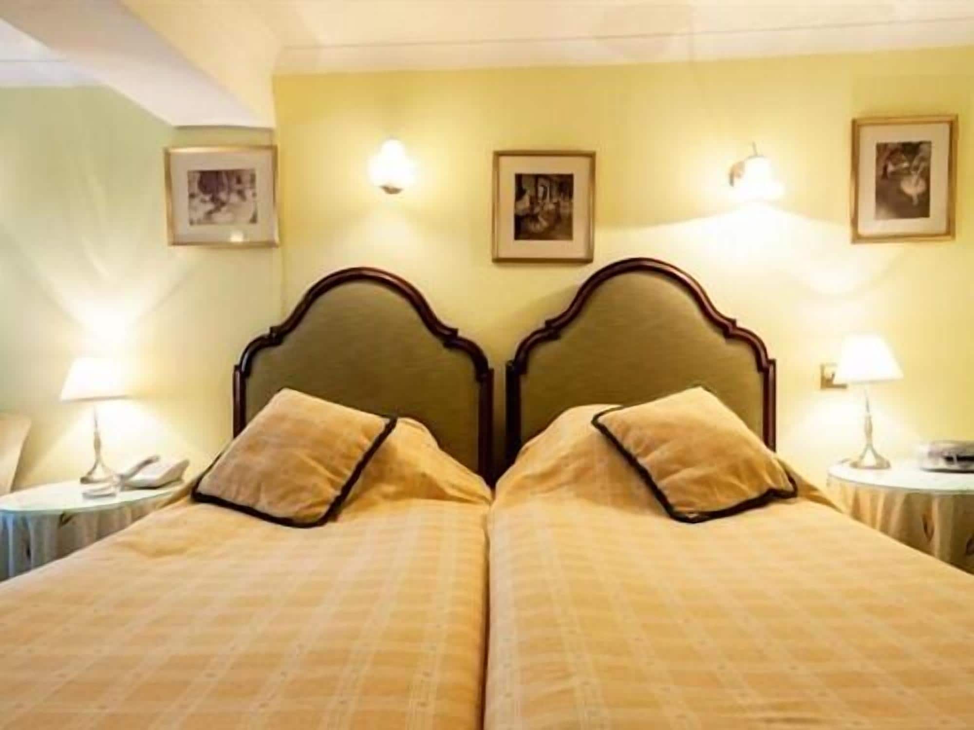 A double bed with a wooden headboard, two bedside tables with lamps, and framed pictures on the wall.