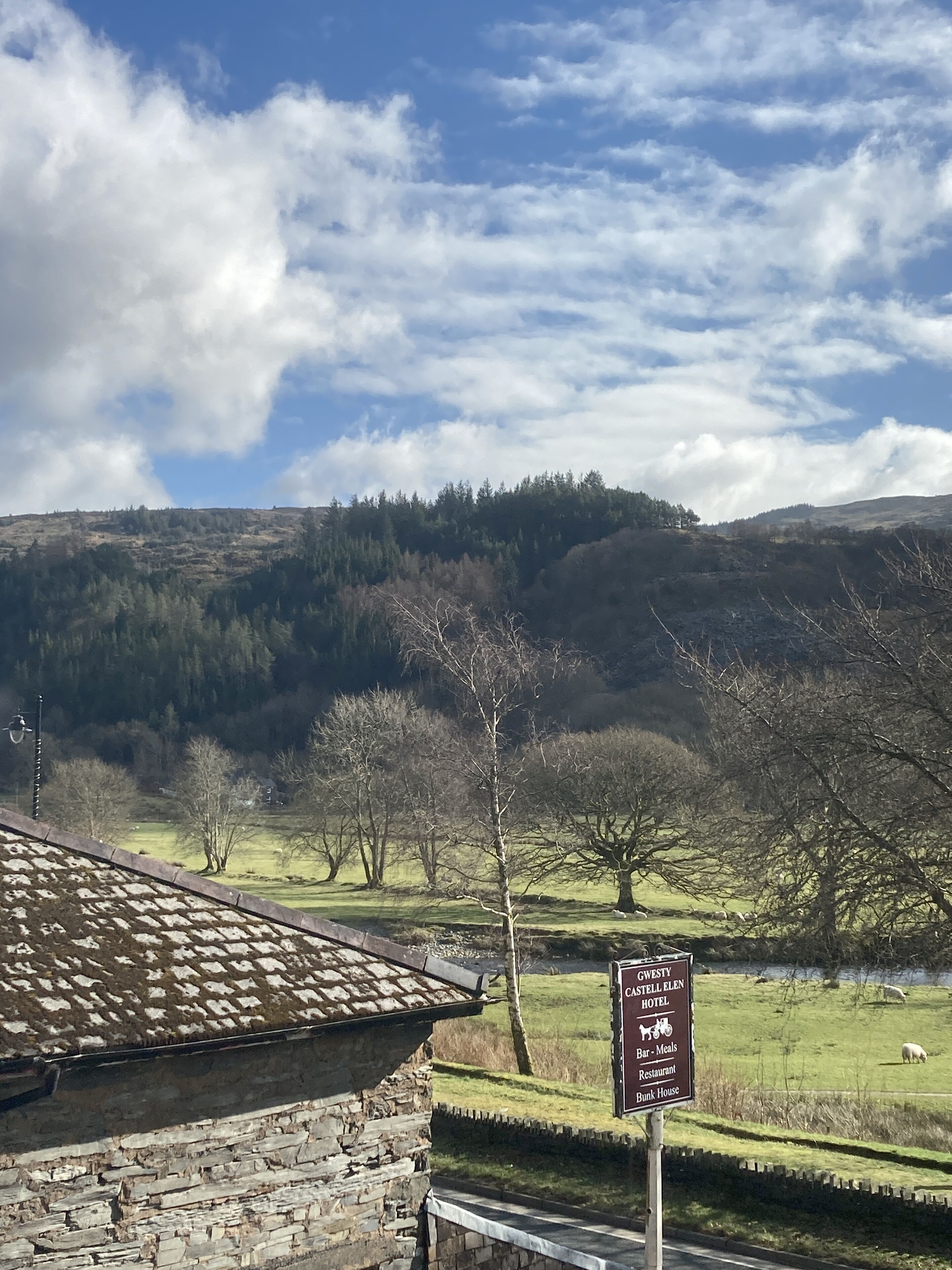 A sign for Gwesti Castell Elen Hotel with amenities including a bar, meals, restaurant, and bunk house.