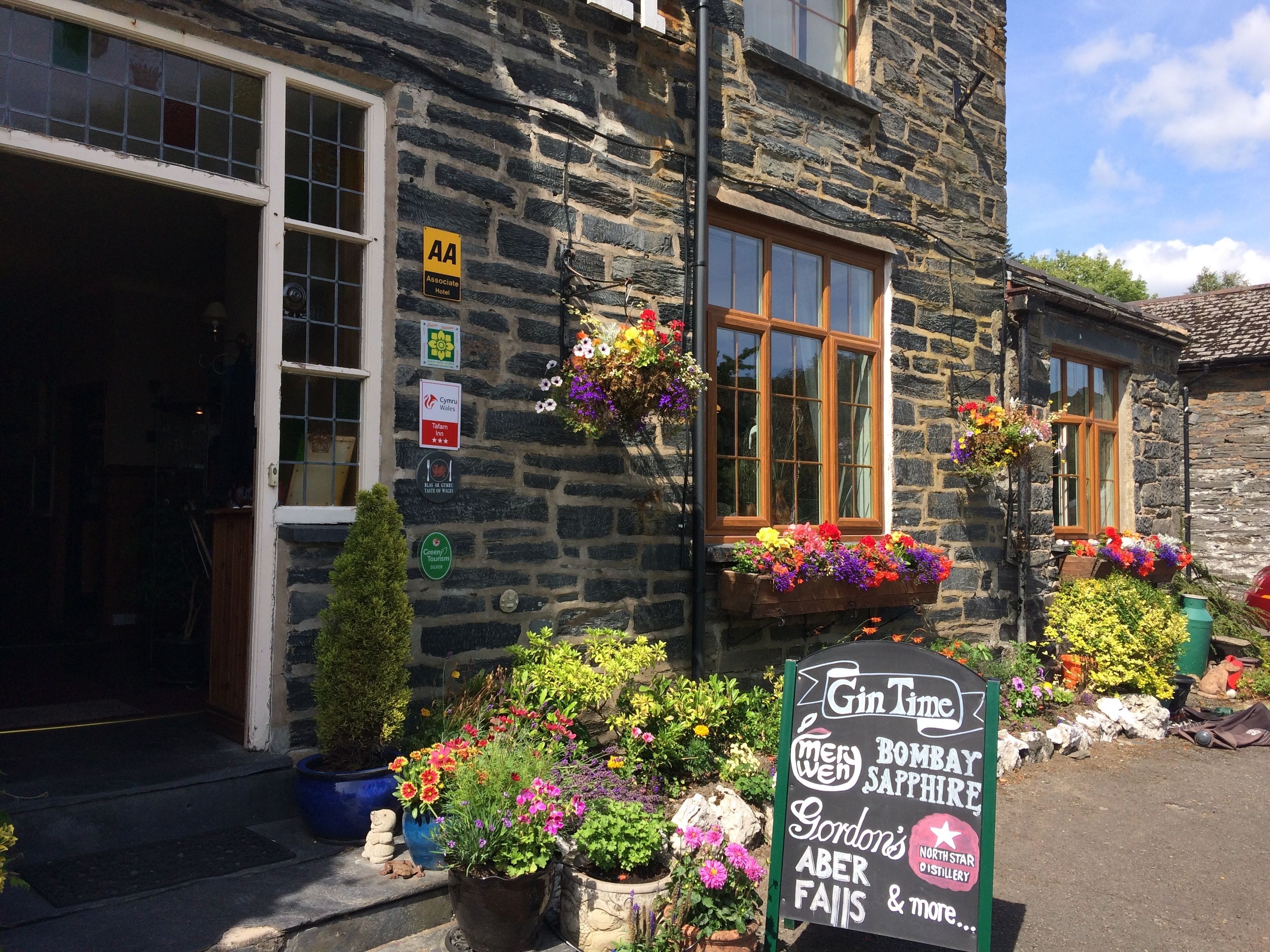 A stone building with a sign for 'Gin Time' and 'Gordon's Aber Falls & more'.