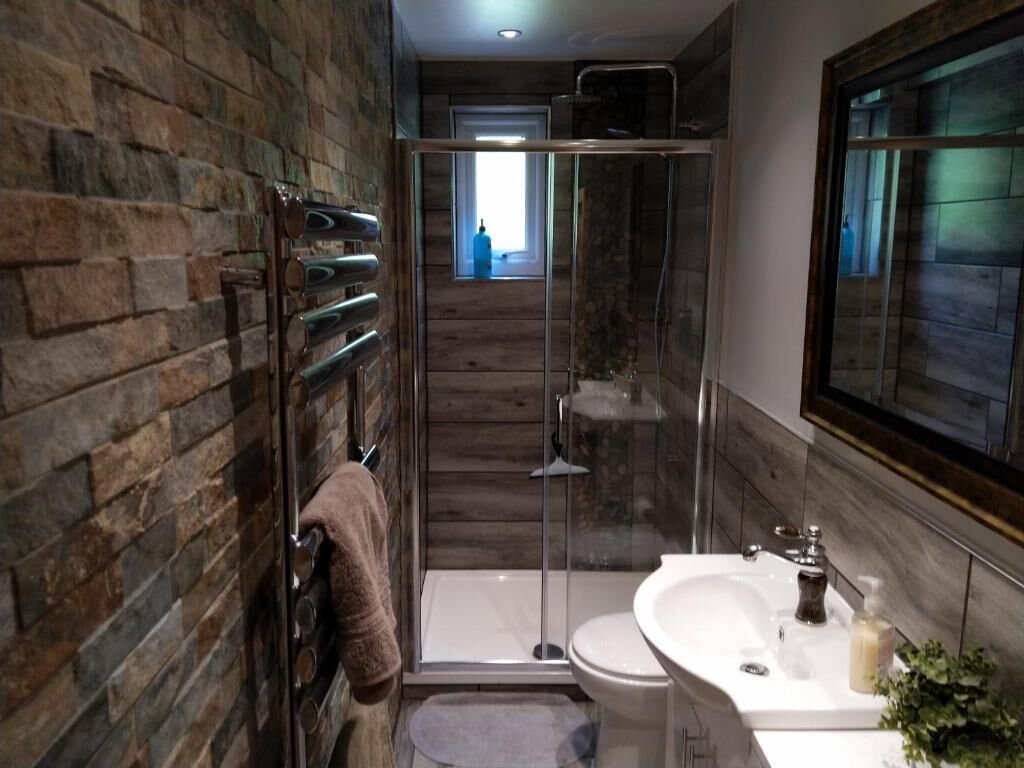A bathroom with a shower, a sink, and a towel rack.