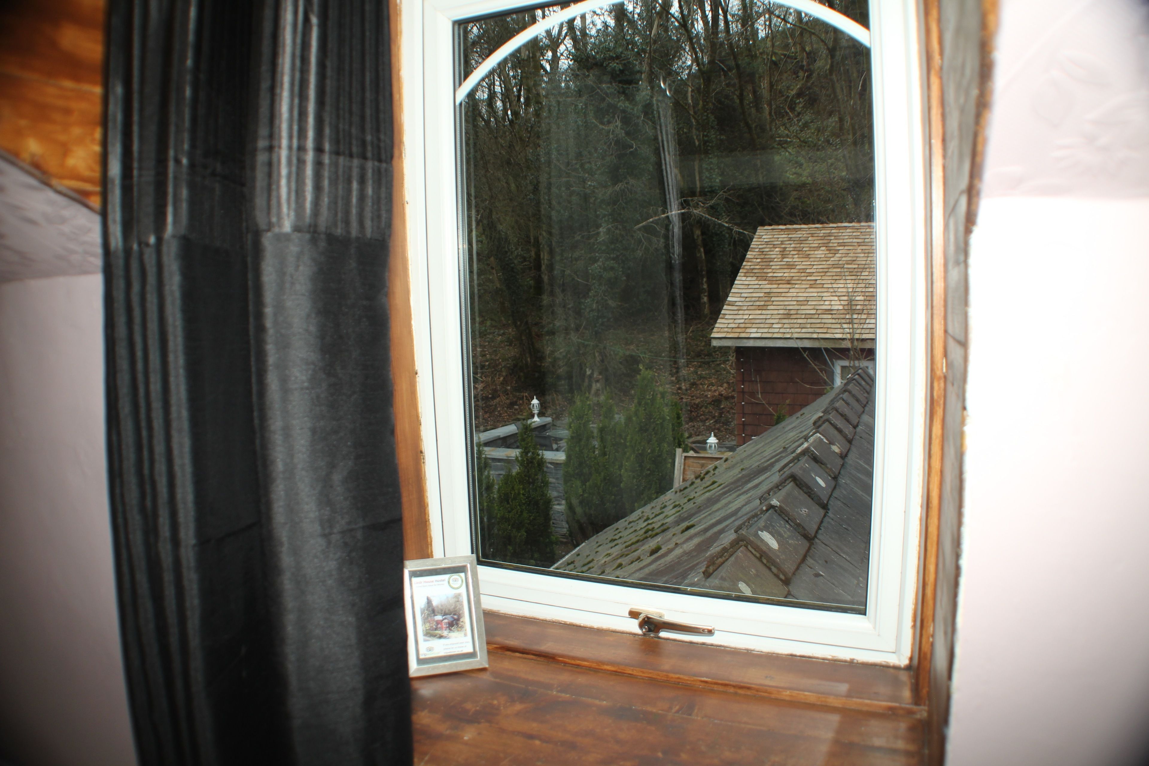 Ein Fenster mit Blick auf ein Haus und Bäume.