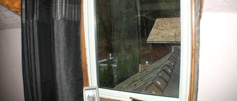 Ein Fenster mit Blick auf ein Haus und Bäume.
