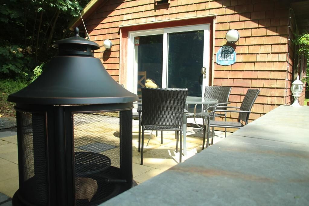An outdoor patio with a grill, wicker chairs, and a welcome sign.
