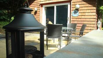 An outdoor patio with a grill, wicker chairs, and a welcome sign.