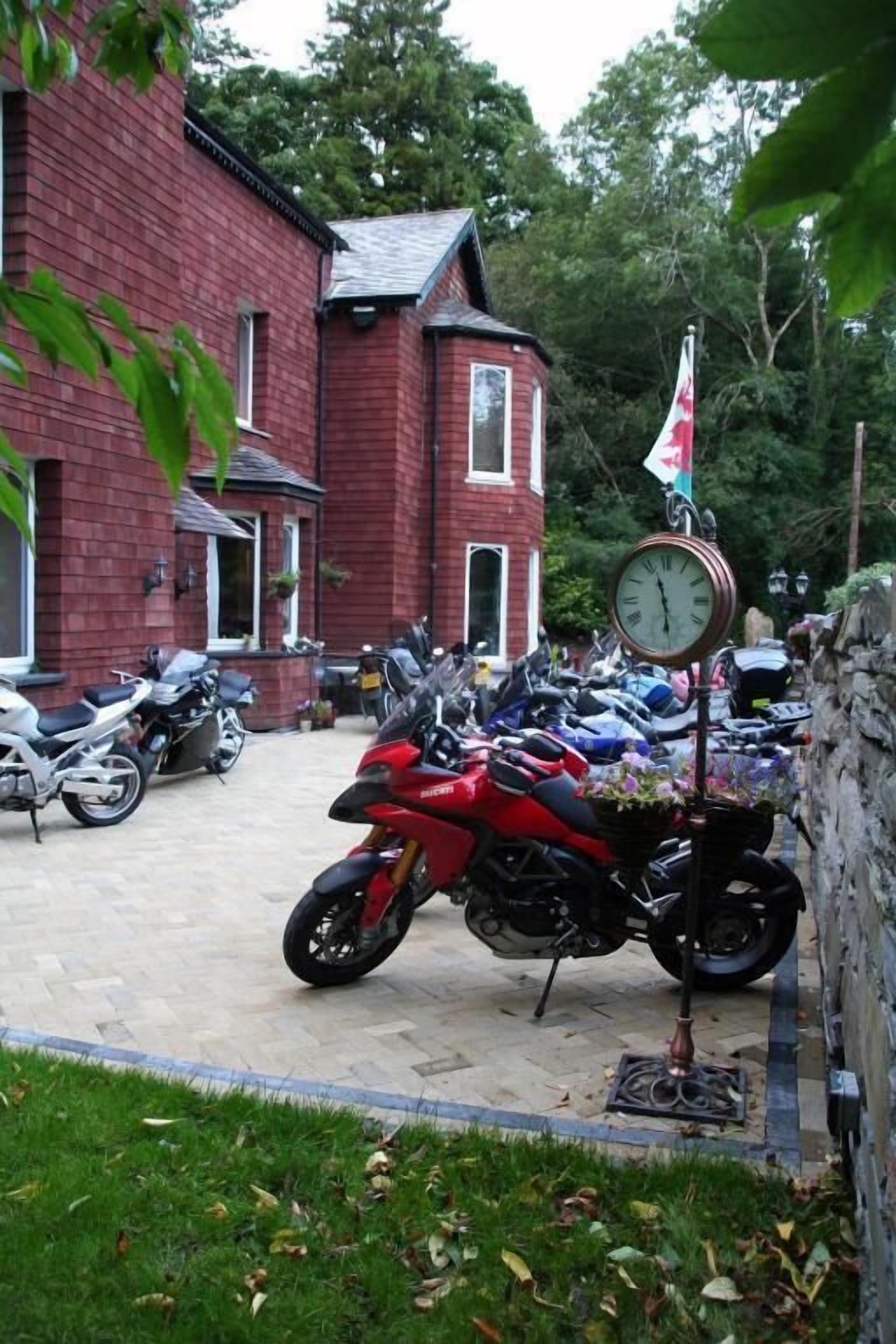 Un edificio de ladrillo rojo con un reloj y una bandera, rodeado de motocicletas estacionadas.