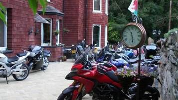 Un edificio de ladrillo rojo con un reloj y una bandera, rodeado de motocicletas estacionadas.