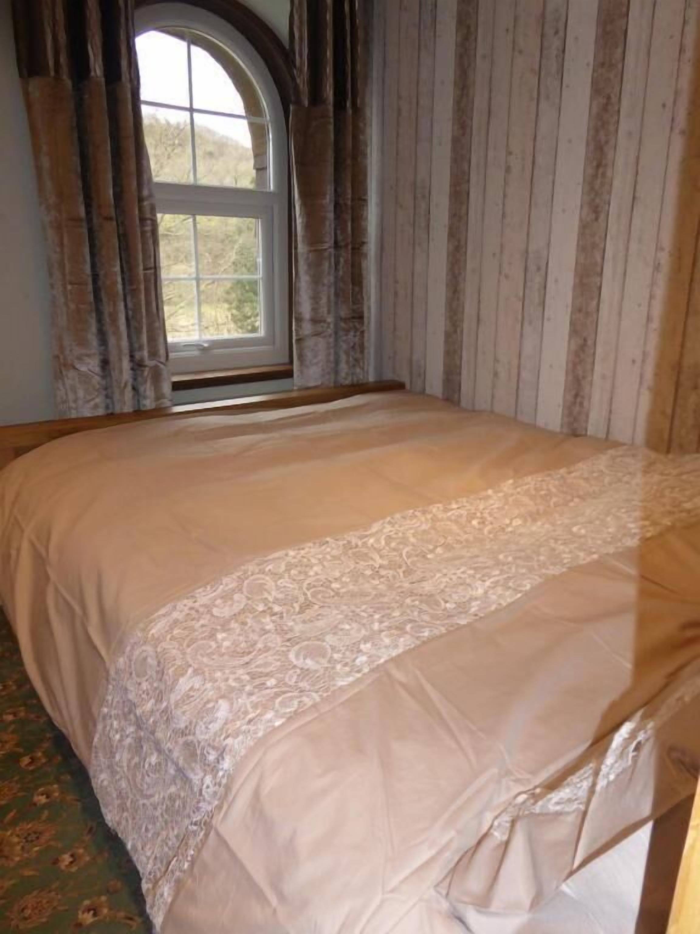 Un dormitorio con una cama grande, una ventana con cortinas y una pared de madera.