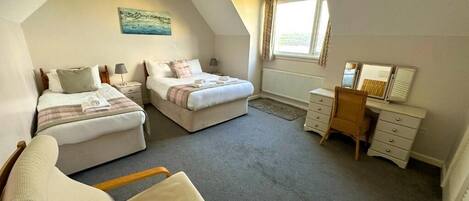 A bedroom with two beds, a desk, a chair, and a window.