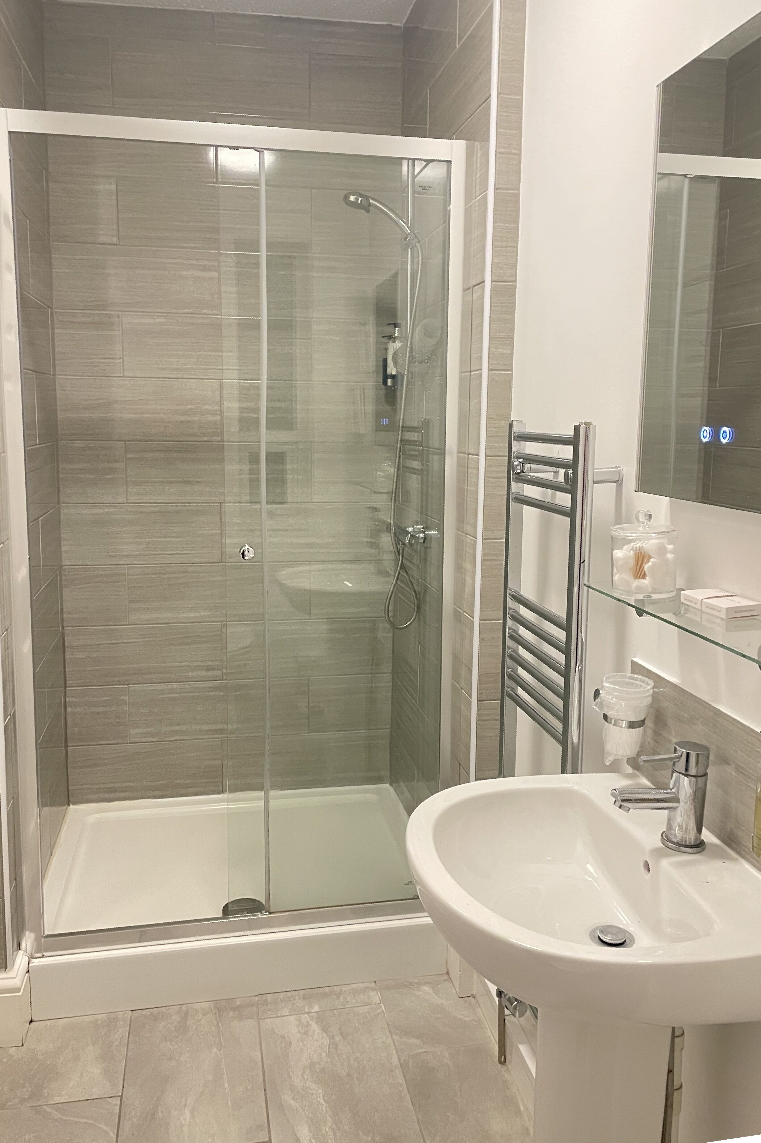A modern bathroom with a glass-enclosed shower, a white sink, and a glass-topped vanity.