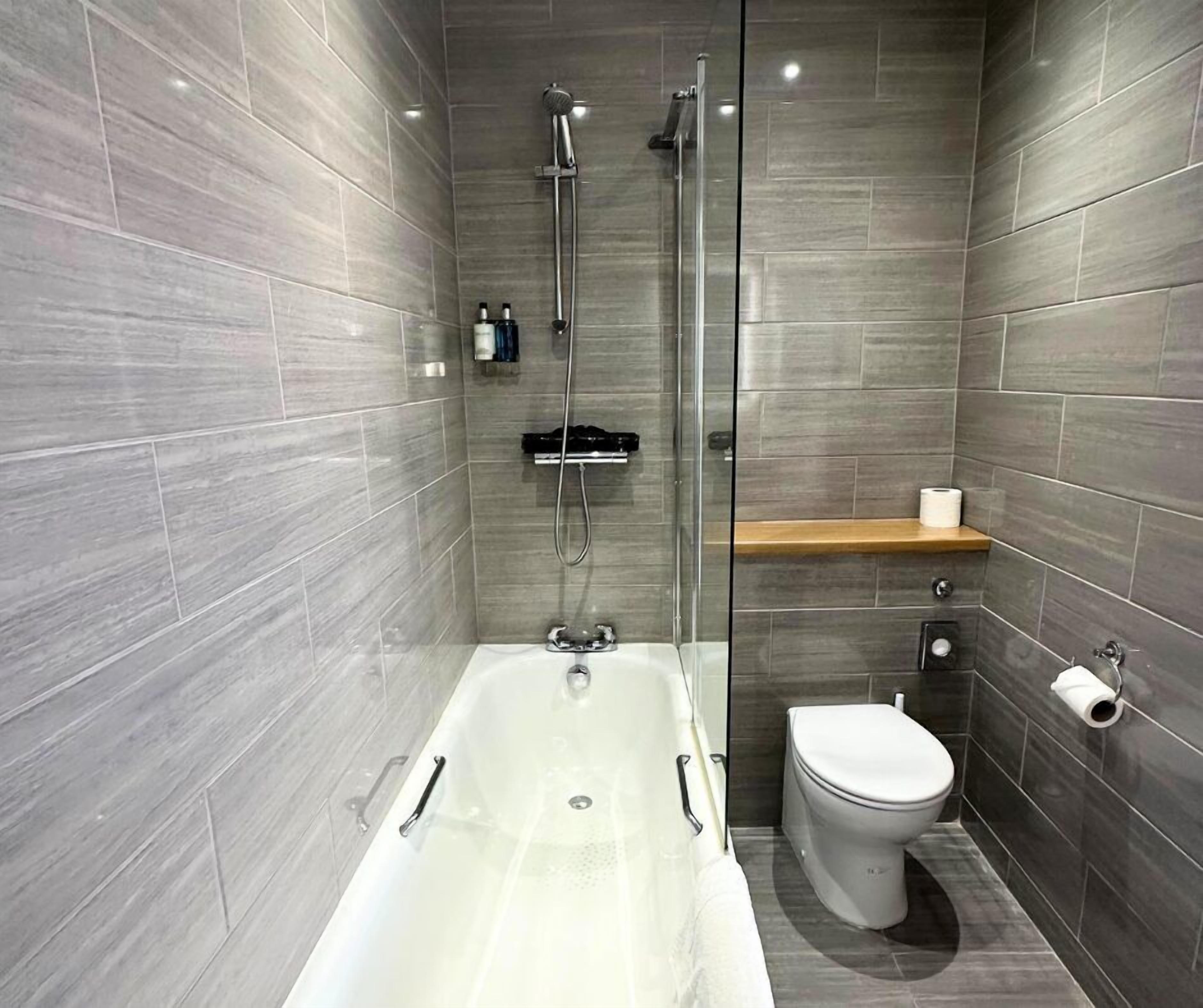 A modern bathroom with a glass-enclosed shower, a bathtub, and a toilet.