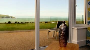 A balcony with a clear view of the sea and a grassy landscape.