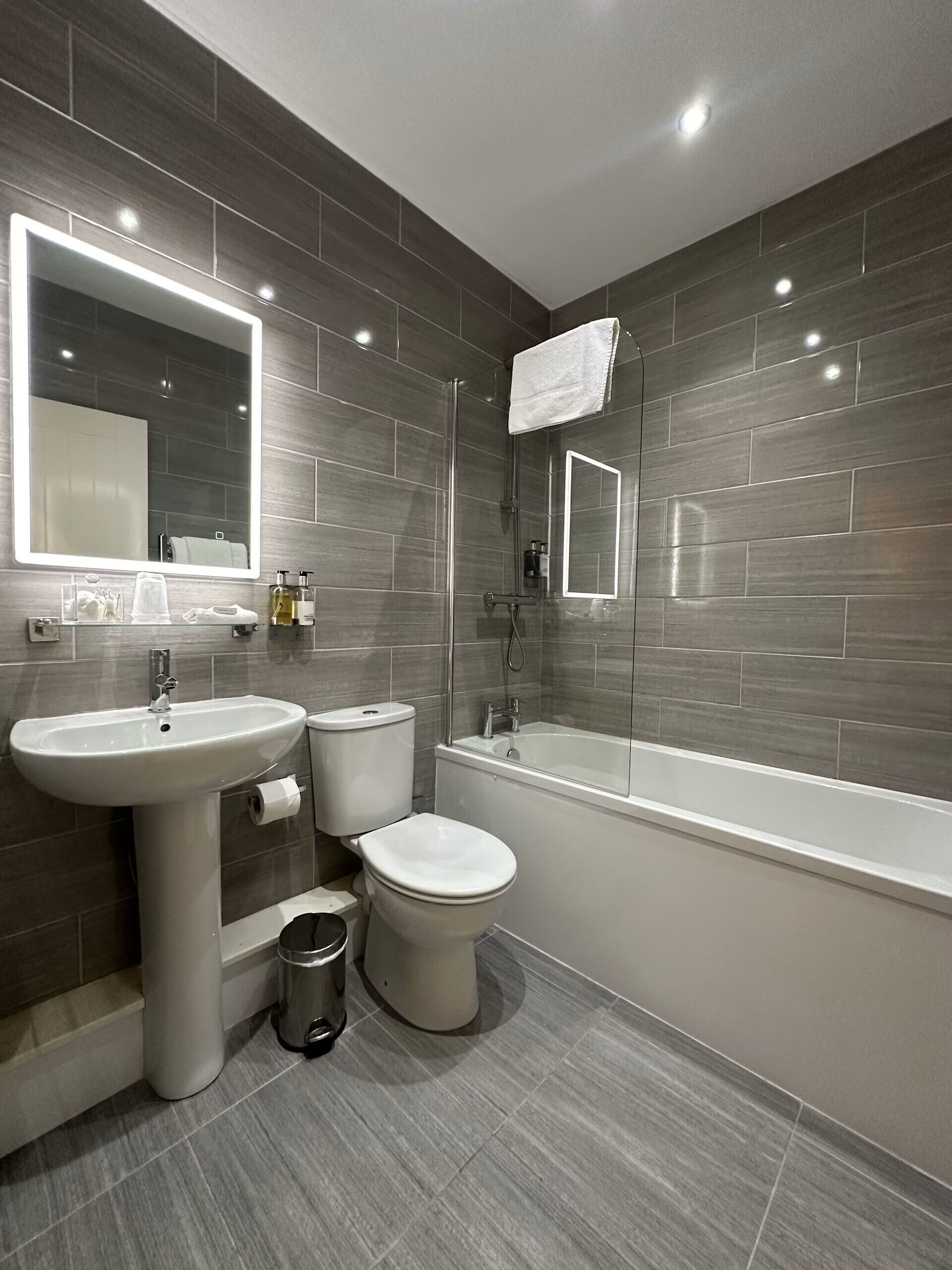 A modern bathroom with a pedestal sink, toilet, and bathtub.