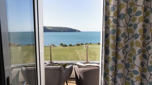 A balcony with two grey chairs, a view of the sea, and a grassy area. - The Cliff Hotel & Spa (Cardigan)