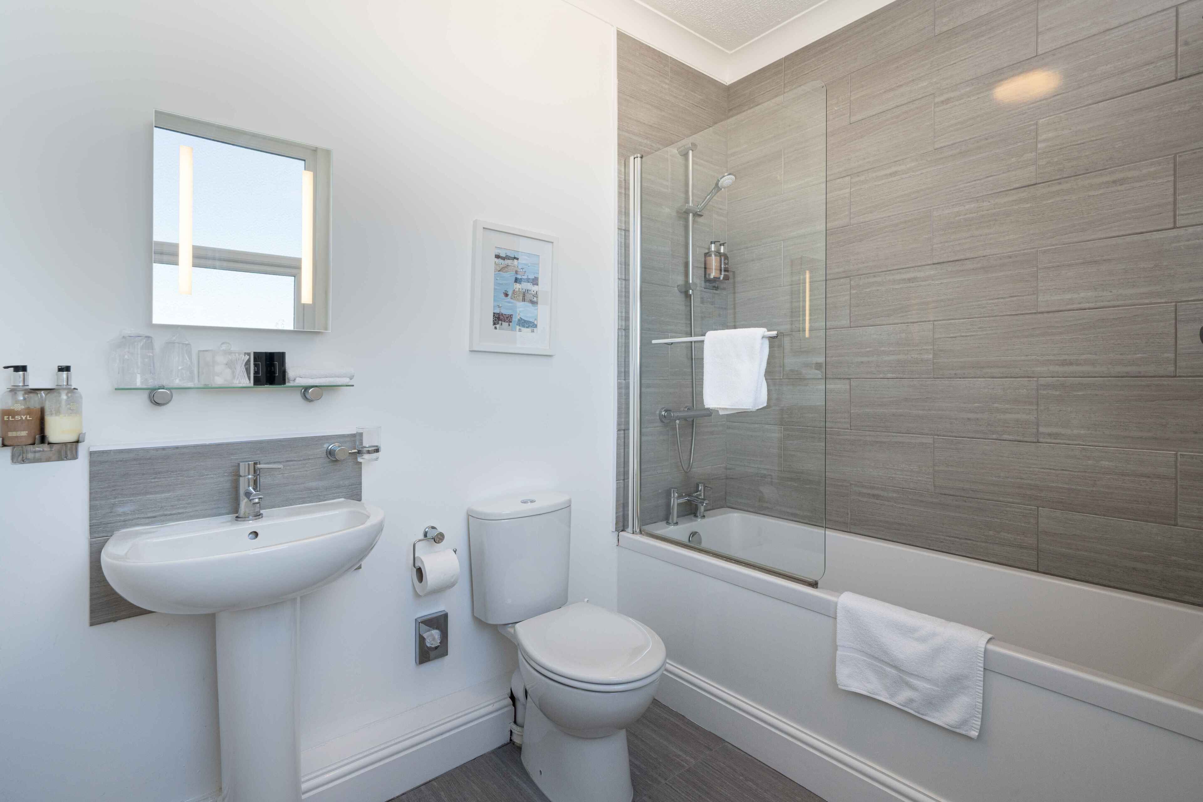 A modern bathroom with a glass-enclosed shower, a white sink, and a toilet.