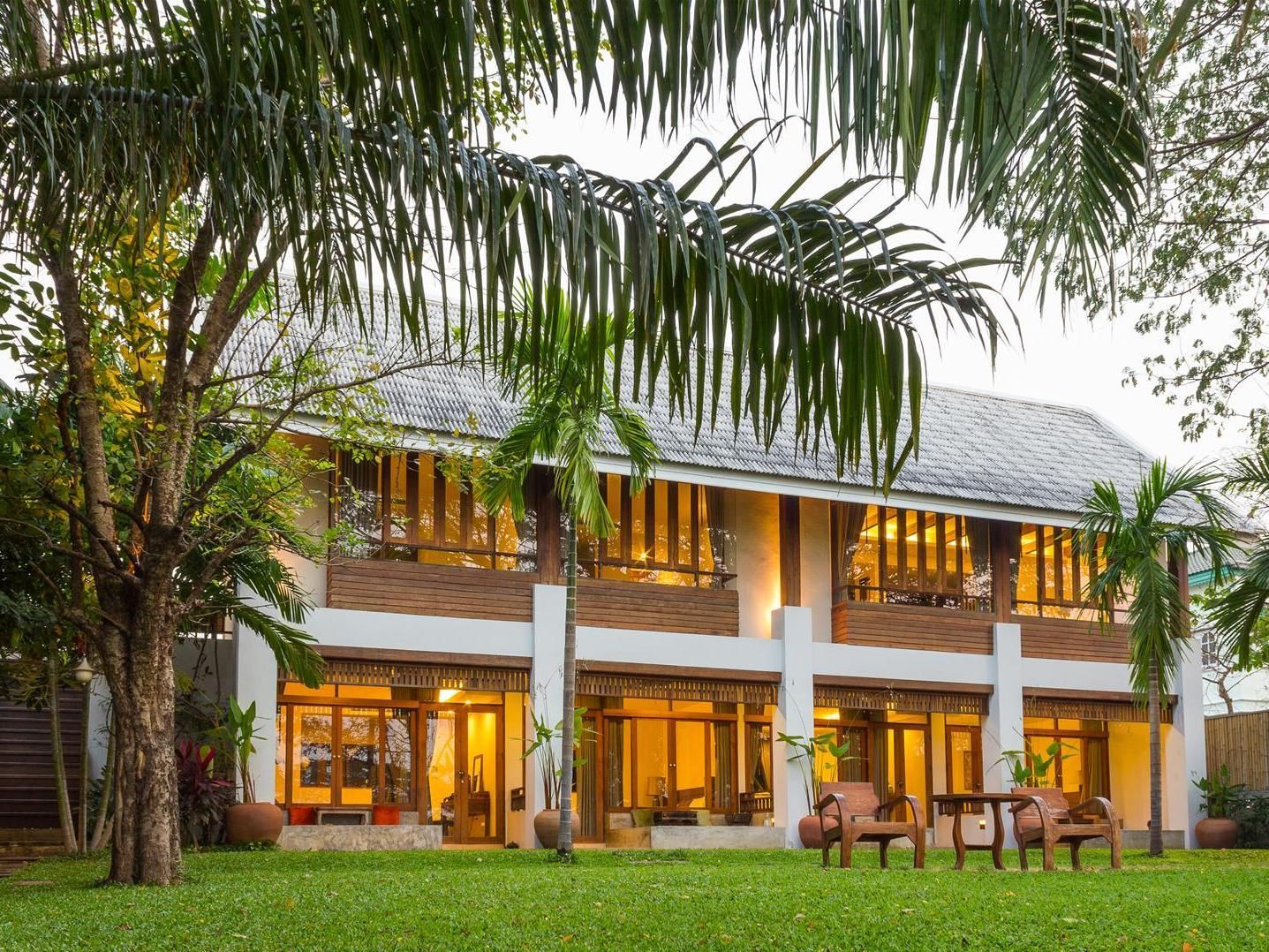 A two-story building with large windows and a flat roof, surrounded by greenery.