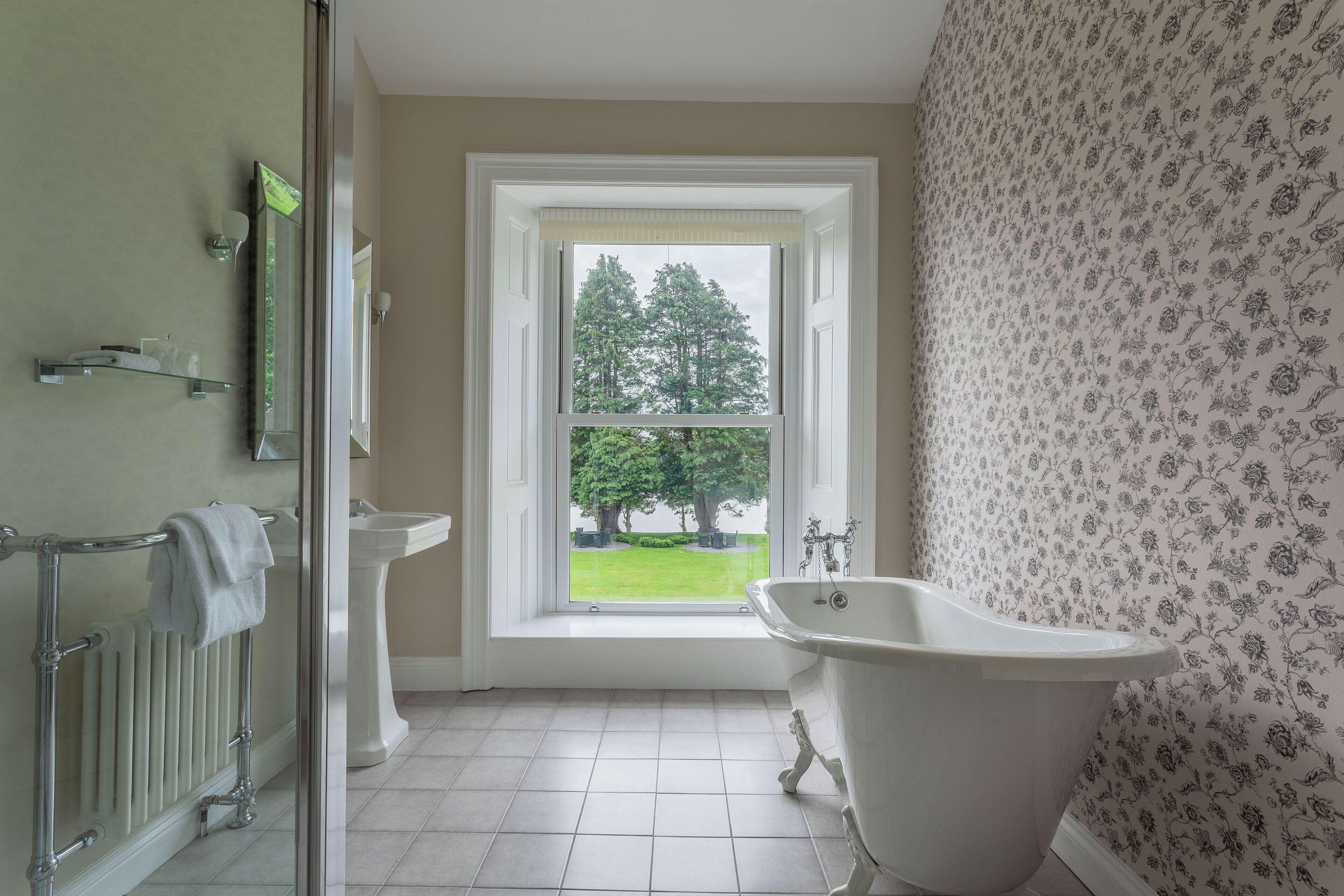 A bathroom with a bathtub, a toilet, and a window with a view of trees.