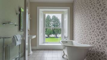 A bathroom with a bathtub, a toilet, and a window with a view of trees.