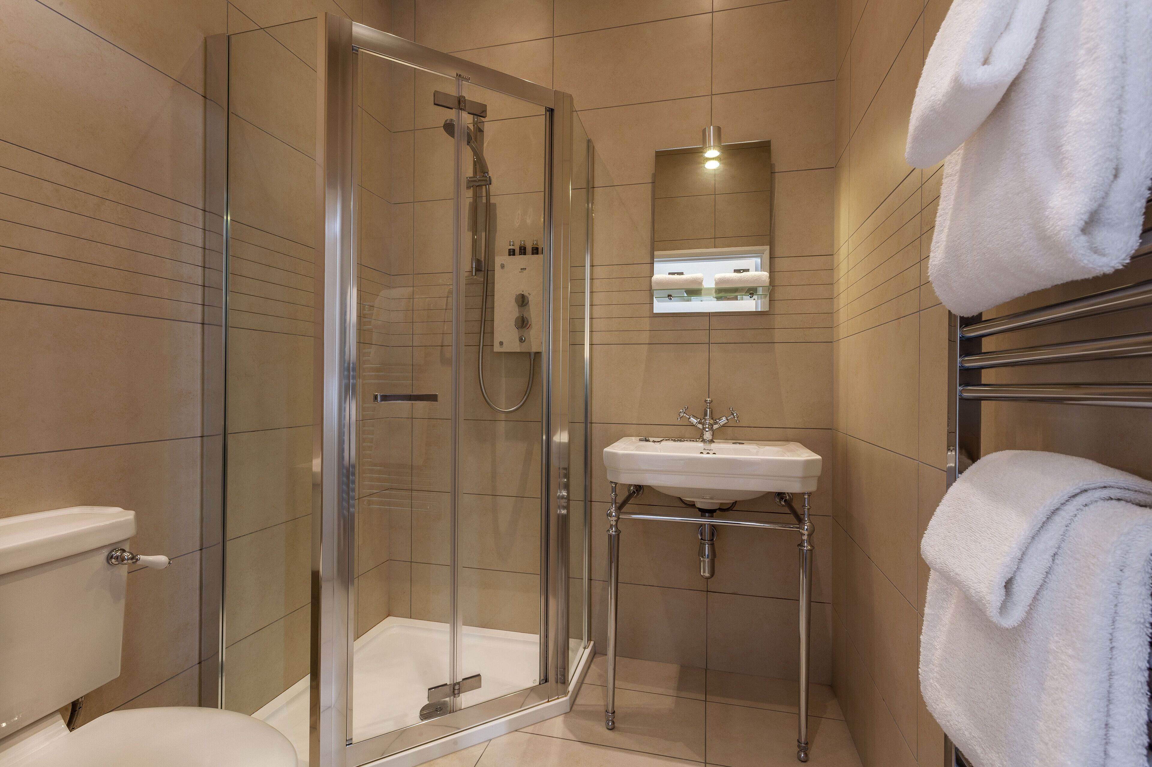 A modern bathroom with a glass-enclosed shower, a white sink, and a towel rack.