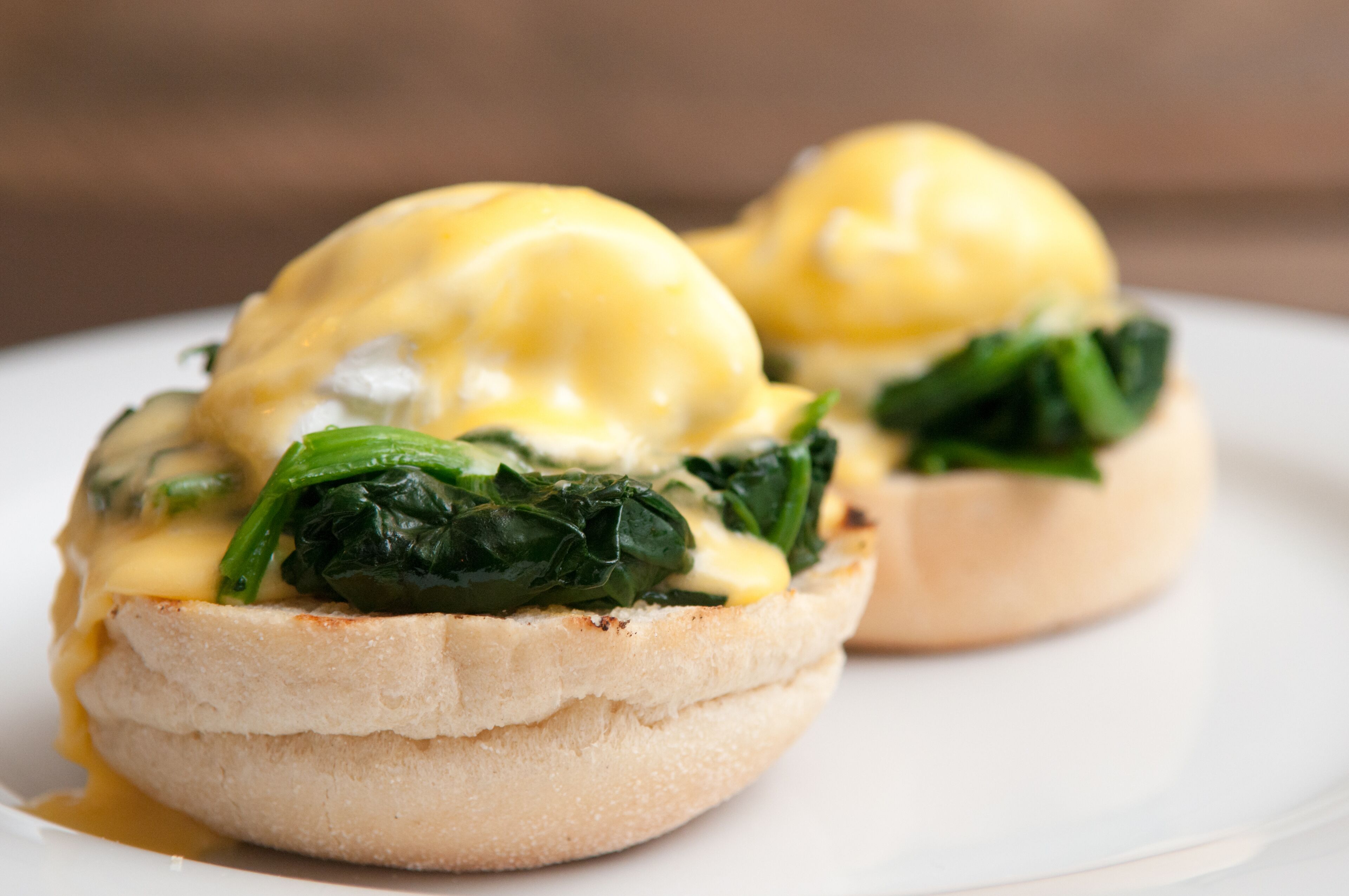 Two eggs benedict sandwiches on a white plate.