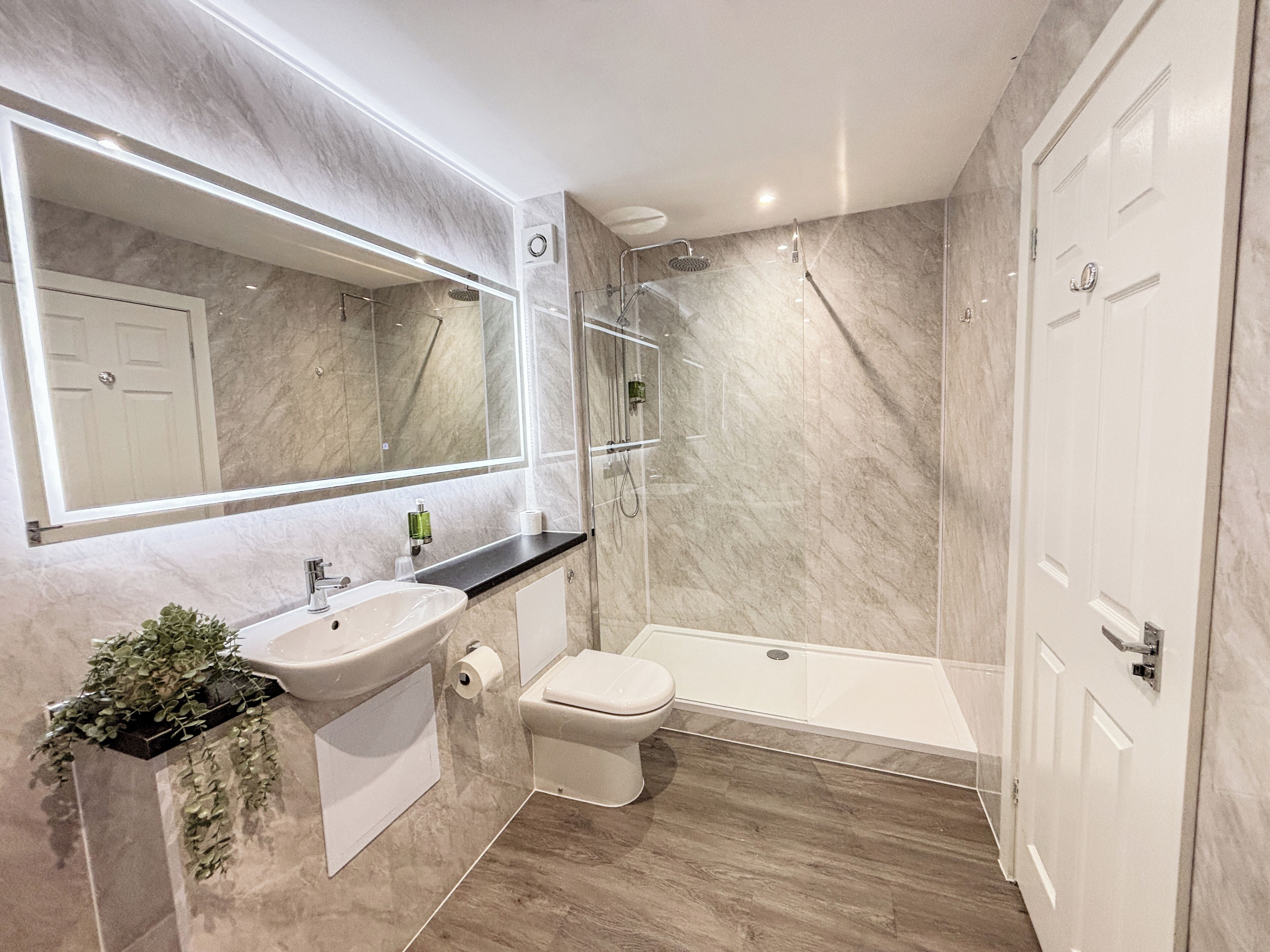 A modern bathroom with a marble sink, toilet, and shower.