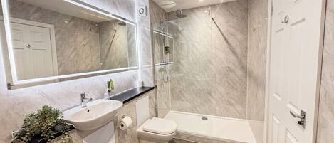 A modern bathroom with a marble sink, toilet, and shower.