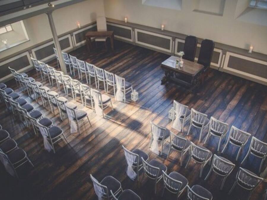 A spacious room with a wooden floor, arranged seating, and a table with chairs.