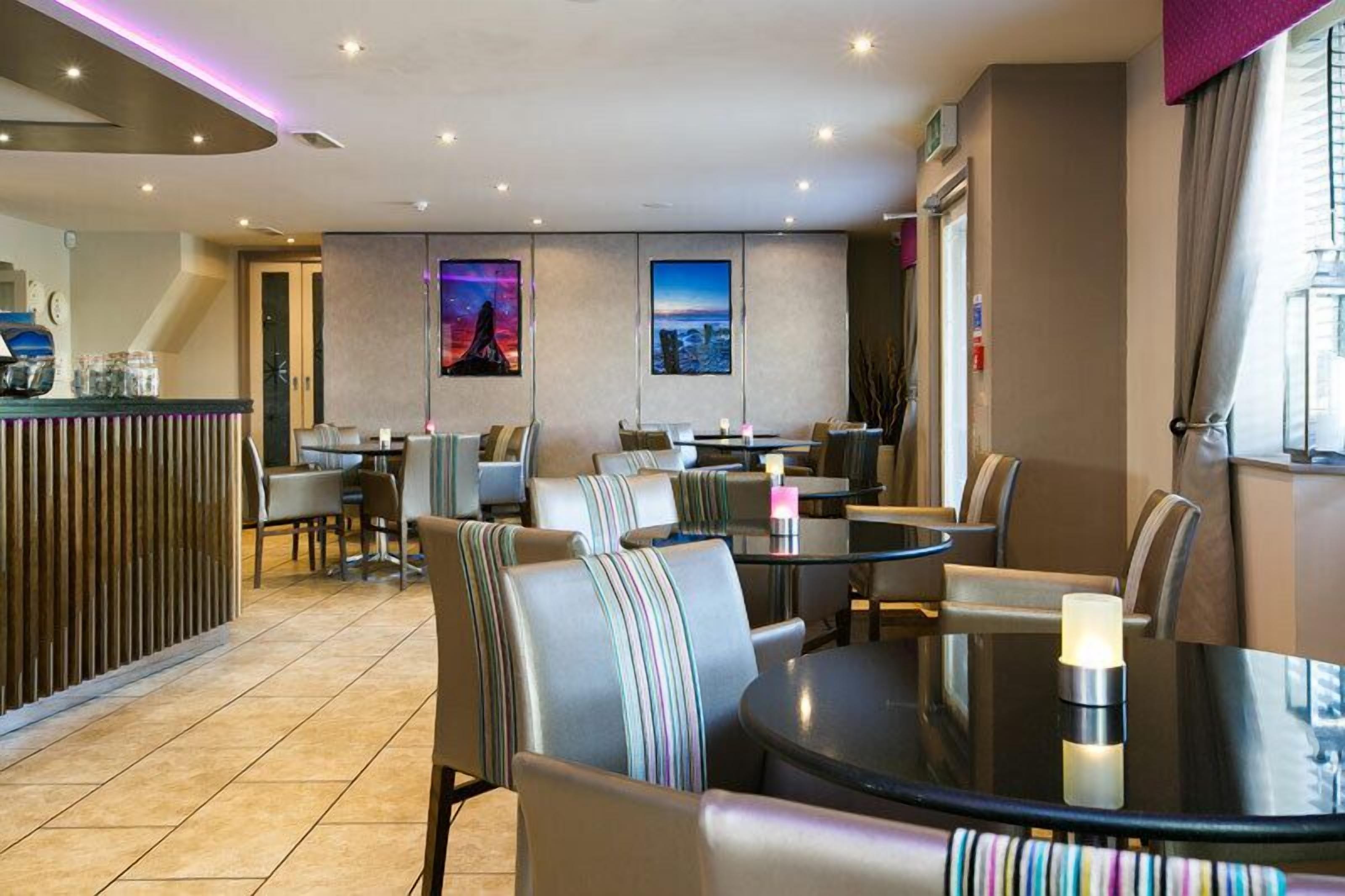 A modern restaurant with a bar area, multiple dining tables, and chairs.