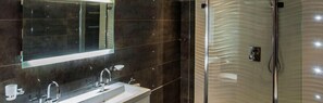 A modern bathroom with a large mirror, a sink, and a shower with a unique textured wall.