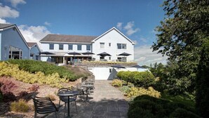 A building with a patio area featuring outdoor seating and umbrellas. - The Plough Rhosmaen (Llandeilo)