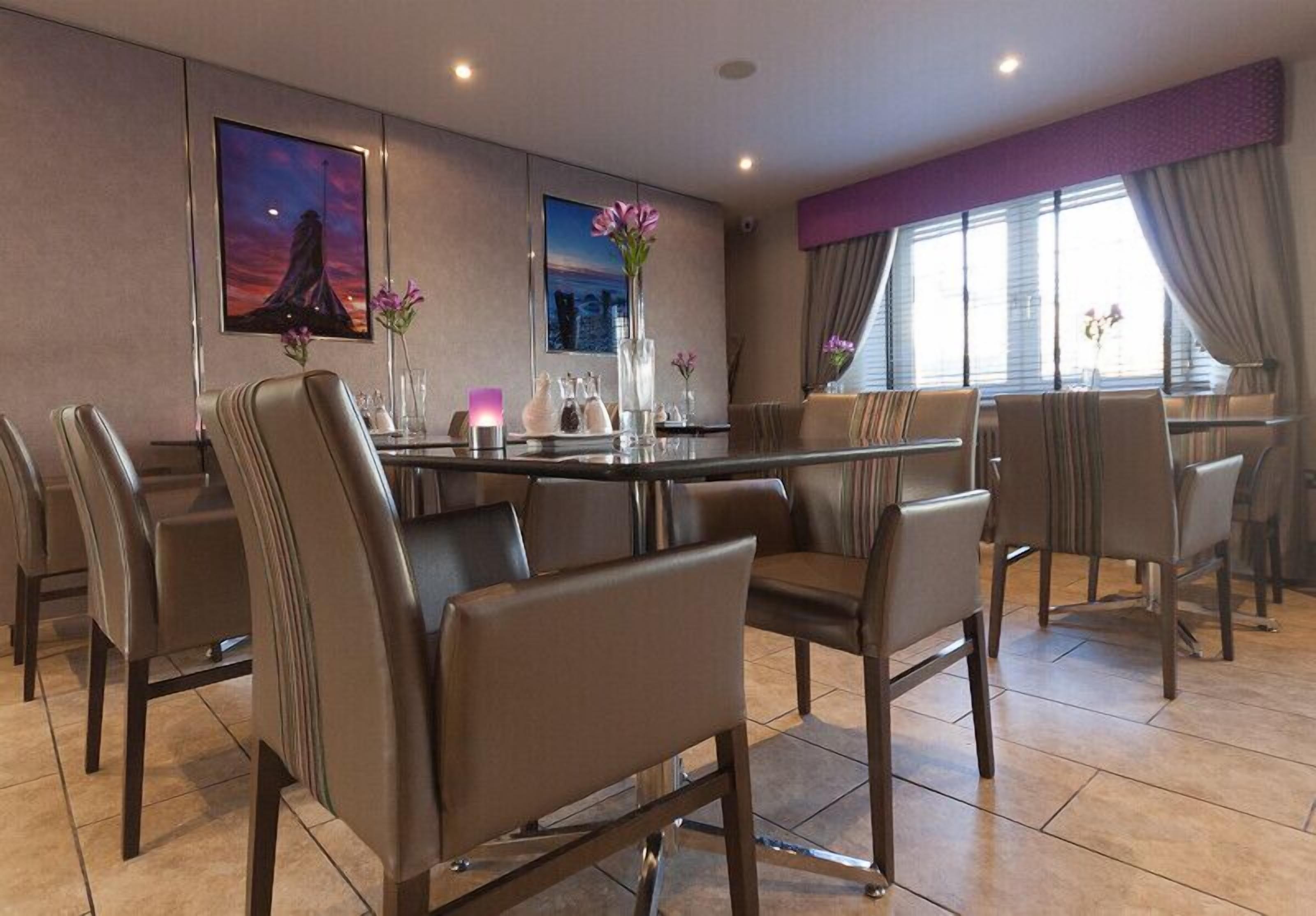 A modern dining area with a round table, leather chairs, and artwork on the walls.